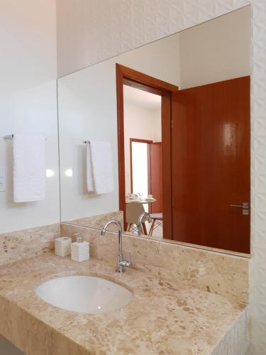 La salle de bains est pourvue d'un lavabo et d'un grand miroir. dans l'établissement Apartamento de Luxo Família, à Prado