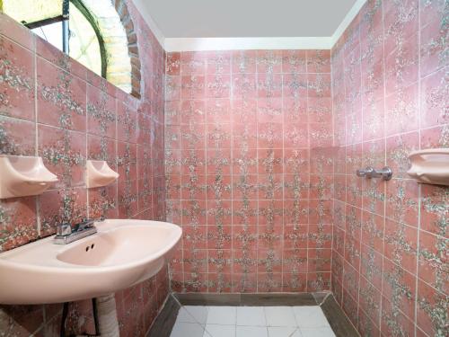 ein Bad mit rot gefliesten Wänden und einem Waschbecken in der Unterkunft Hotel del Carmen in Tlalpujahua