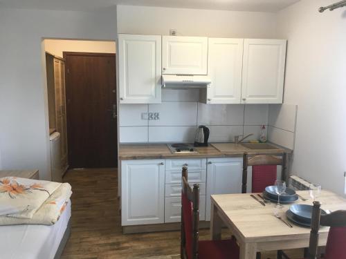 a kitchen with white cabinets and a table and a dining room at Zajazd Tadeo in Pietrzykowice