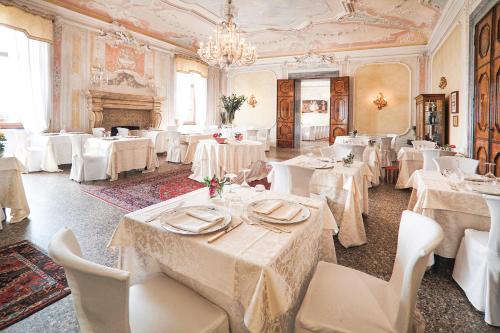 a restaurant with white tables and chairs and a chandelier at CastelBrando in Cison di Valmarino