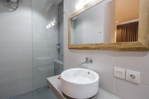 een witte badkamer met een wastafel en een spiegel bij The jero 18 kuta guest house in Kuta