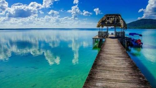 a dock with chairs and a straw umbrella on the water at La Posada De Don Jose in Flores