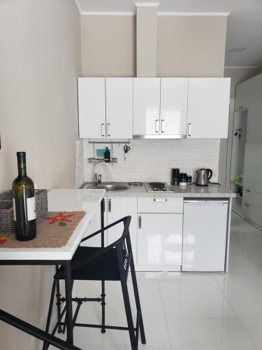 a kitchen with white cabinets and a table with a bottle of wine at Tatiana Gudauri in Gudauri