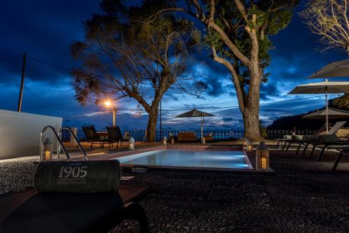 a swimming pool at night with tables and umbrellas at 1905 Zino's Palace in Ponta do Sol
