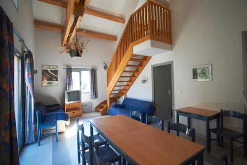 sala de estar con escalera, mesa y sillas en Gîtes du Presbytère en Saint-Dalmas-le-Selvage