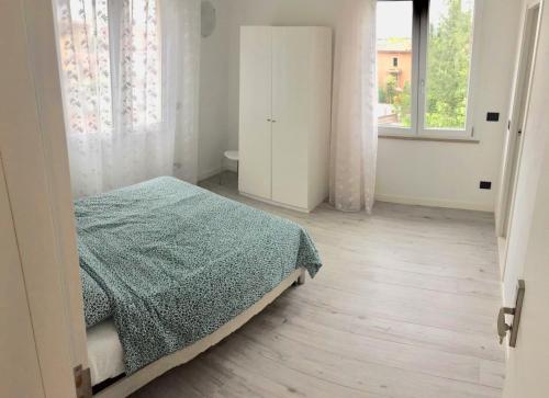 ein weißes Schlafzimmer mit einem Bett und einem Fenster in der Unterkunft PeschieraView DUPLEX x7 in Peschiera del Garda