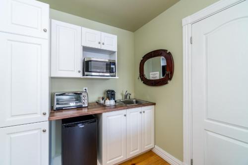 a kitchen with white cabinets and a sink and a microwave at Goéliche hotel et appartement in Saint-Laurent-de-l'ile d'Orleans