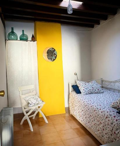 a bedroom with a bed and a chair and a yellow wall at Casilla Cantón in Canjáyar
