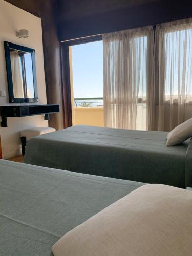 a hotel room with two beds and a window at Apartamentos Guadiana in Monte Gordo