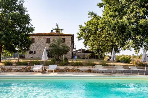 a pool with chairs and umbrellas in front of a building at Agriturismo Podere Campinovi in Colle Val D'Elsa