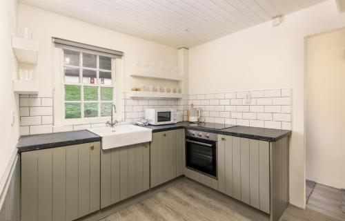 een witte keuken met een wastafel en een magnetron bij Fern Cottage in Killinaboy