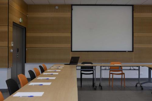 a large conference room with a white screen and tables and chairs at ibis Styles Vierzon in Vierzon