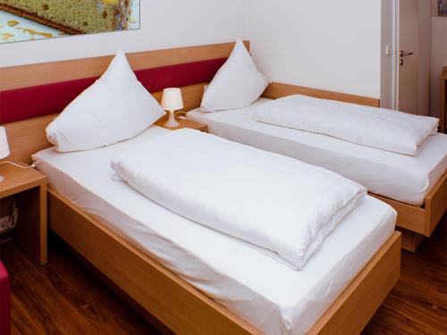 two beds in a room with white pillows at Gästehaus Eschers Eiswerk in Annweiler am Trifels