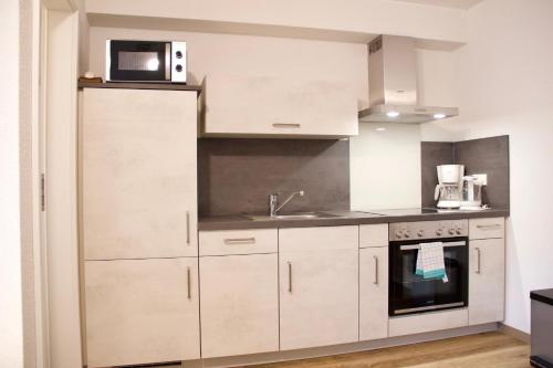 a kitchen with white cabinets and a microwave at Herzog Wolfgang Studios- Zentral, Modern, Freundlich in Zweibrücken