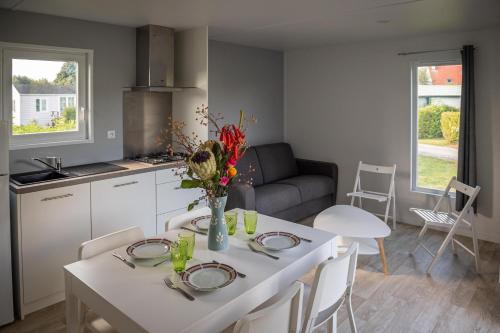 une cuisine et un salon avec une table et des chaises blanches dans l'établissement Les Prairies de la Mer - Baie de Somme, à Favières