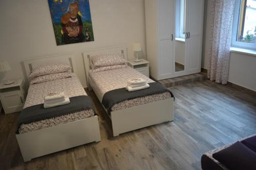two beds in a small room with wooden floors at Istrabella Apartment in Koper