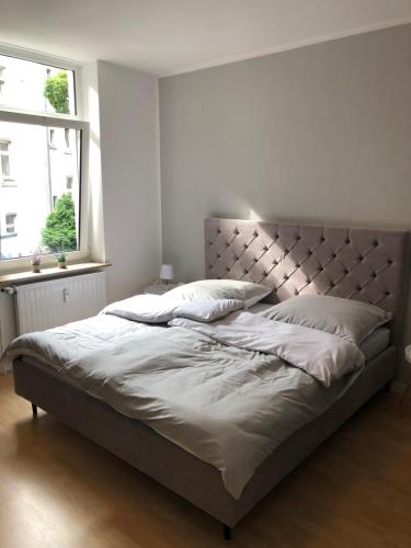 1 dormitorio con 1 cama grande, cabecero y ventana en RÜ Business Apartments & Suites en Essen