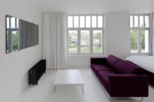 sala de estar con sofá púrpura y cama en Zenden Hotel Maastricht, en Maastricht