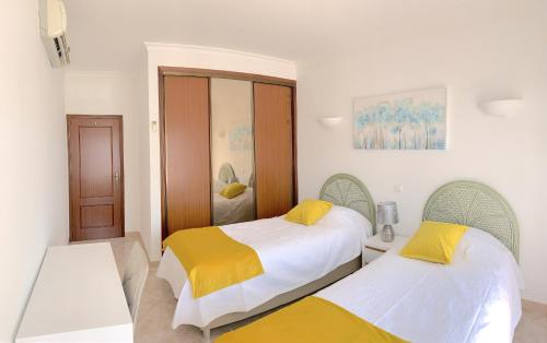 1 dormitorio con 2 camas con sábanas blancas y amarillas en Fournier Apartment - Praia da Luz, en Luz