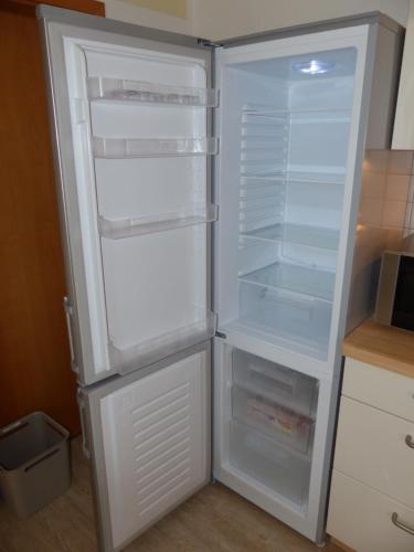 an empty refrigerator with its door open in a kitchen at Komfort Ferienwohnung II Wolfhagen in Wolfhagen