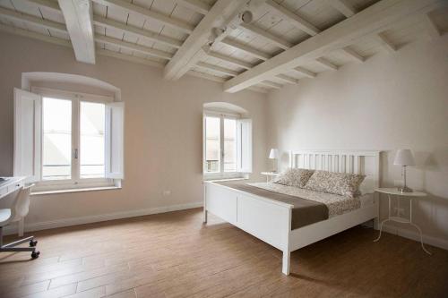 een witte slaapkamer met een bed en 2 ramen bij Maffia Luxury in Florence