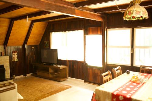 a dining room with a table and some windows at Chalé do Vale Encantado in Campos do Jordão