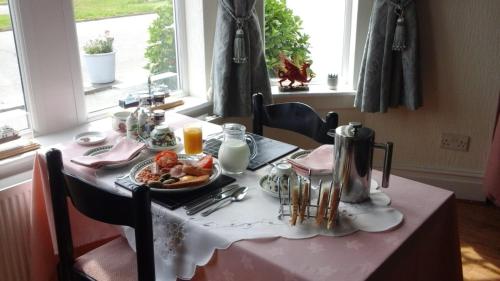 a table with a plate of food on a pink table cloth at Craig-y-Mor in Criccieth