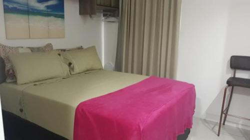 um quarto com uma cama com um cobertor rosa em Flat em Cabo Frio em Cabo Frio
