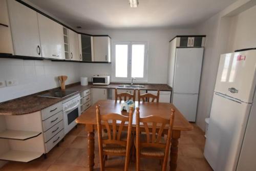 a kitchen with a table and chairs and a white refrigerator at Villa Bonita en Aguilas Murcia con piscina privada in Águilas