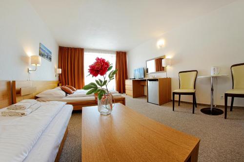 a hotel room with a vase with a red flower on a table at Penzión Dubo in Liptovský Mikuláš