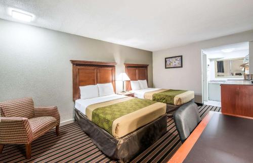 a hotel room with two beds and a chair at Rodeway Inn in Saint Joseph