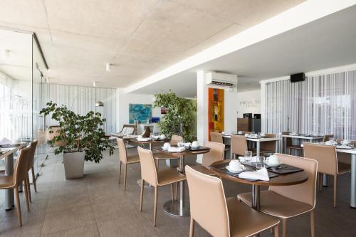 a dining room with tables and chairs and plants at UY Proa Sur Hotel in La Paloma