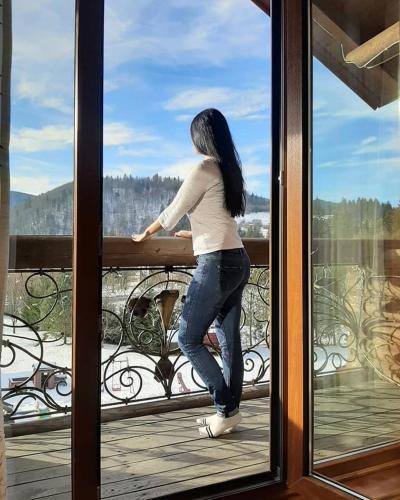 a woman standing on a balcony looking out of a window at Panska Hata in Yaremche