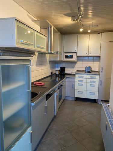 a large kitchen with white cabinets and appliances at Ferienhof Kröger in Bielefeld