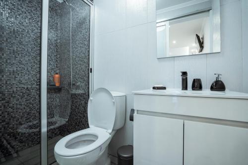 a white bathroom with a toilet and a shower at Central Praia Beach in Praia da Vitória