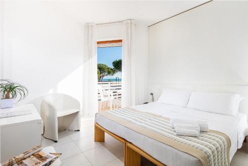 a white bedroom with a bed and a view of the ocean at Hotel Bristol in Lignano Sabbiadoro