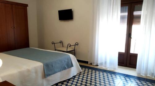a bedroom with a bed and a tv and a window at Alojamiento Rural La Estrella de David in Almagro
