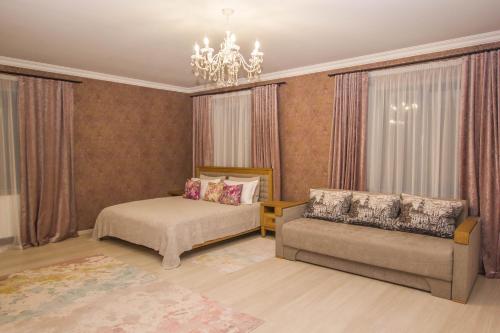 a bedroom with a bed and a couch and a chandelier at Старий Тудорів in Fedorovka