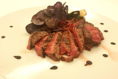 a white plate with a piece of meat on it at Hotel Bristol in Lignano Sabbiadoro