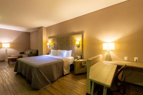 Cette chambre comprend un lit et un bureau. dans l'établissement Hotel Glow Point - Mulza, à León