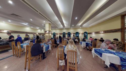 a group of people sitting at tables in a restaurant at Falcon Hills Hotel in Sharm El Sheikh