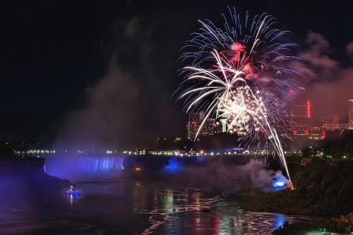 a fireworks display over the water with a city at Country Inn & Suites by Radisson, Niagara Falls, ON in Niagara Falls