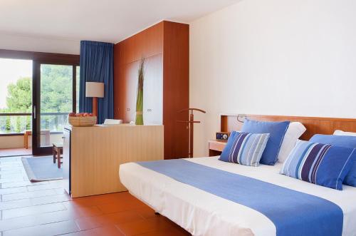 ein Schlafzimmer mit einem großen Bett mit blauen und weißen Kissen in der Unterkunft Almadraba Park Hotel in Roses