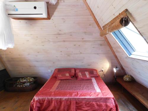 a bedroom with a red bed in a attic at Piramide in Punta Del Diablo