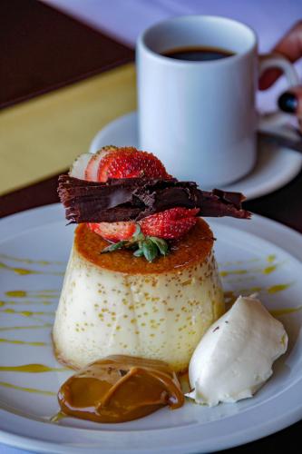 a dessert with strawberries on a plate with a cup of coffee at Sol del Nahuel - Hotel & Spa in San Carlos de Bariloche