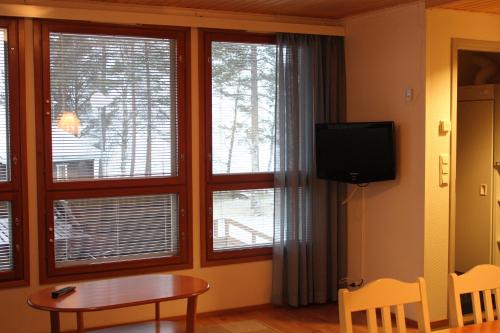 a living room with windows and a table and a tv at Camping Merihelmi in Myllykangas