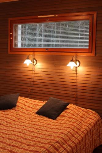 a bedroom with two beds and two lights on the wall at Camping Merihelmi in Myllykangas