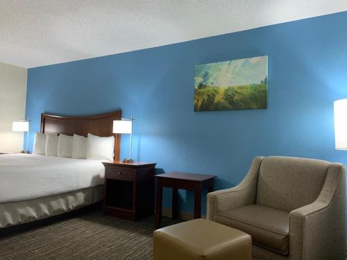 a hotel room with a bed and a chair at Best Western Inn & Suites Monroe in Monroe