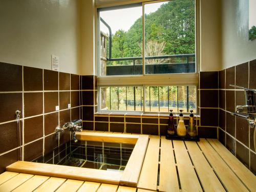 uma casa de banho com uma banheira e uma janela em Shirakabeso em Izu