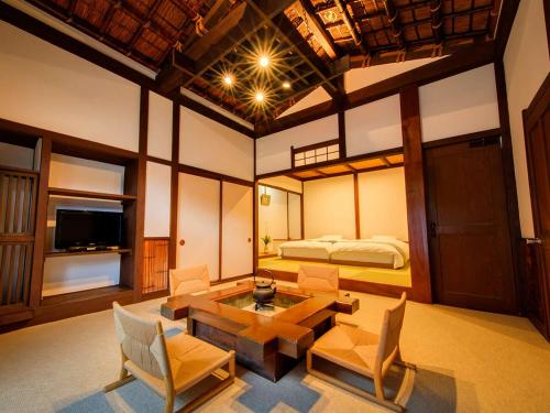 uma sala de estar com uma cama, uma mesa e cadeiras em Shirakabeso em Izu